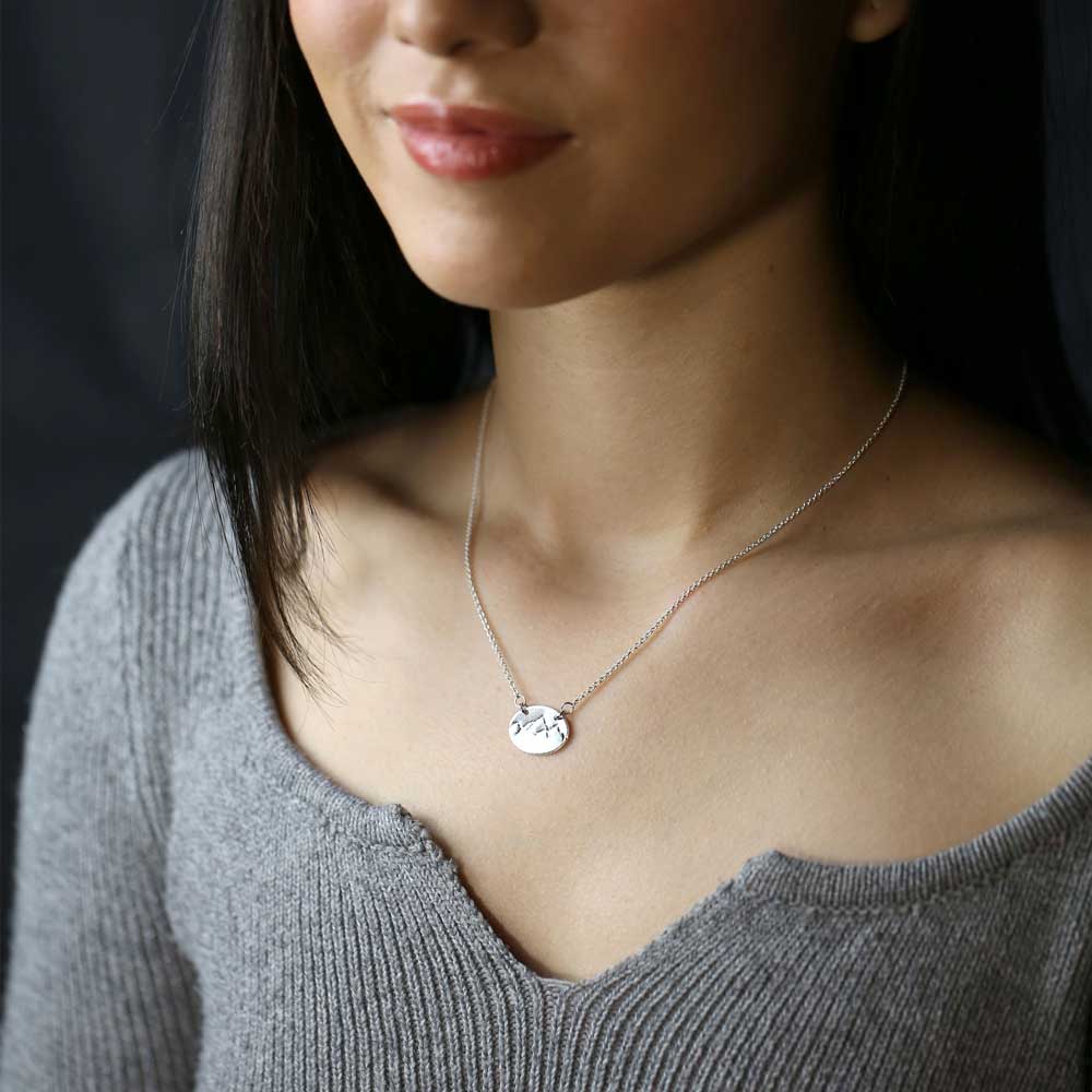 Woman wearing silver mountain necklace.