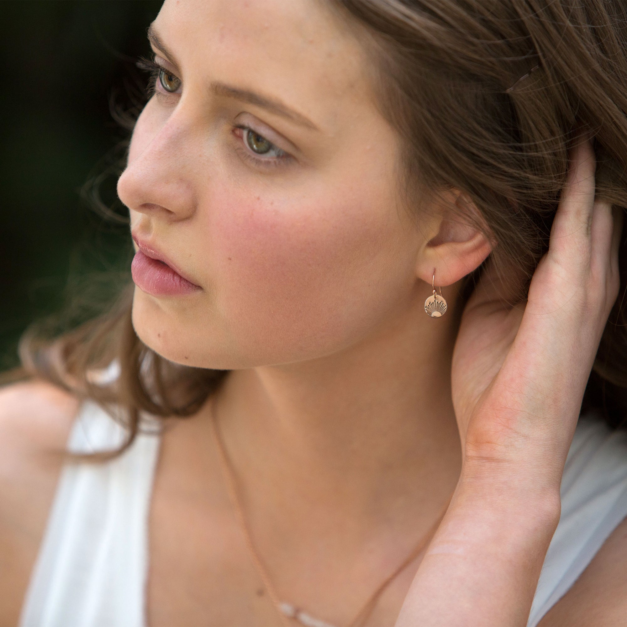 Woman wearing gold sunburst earrings.