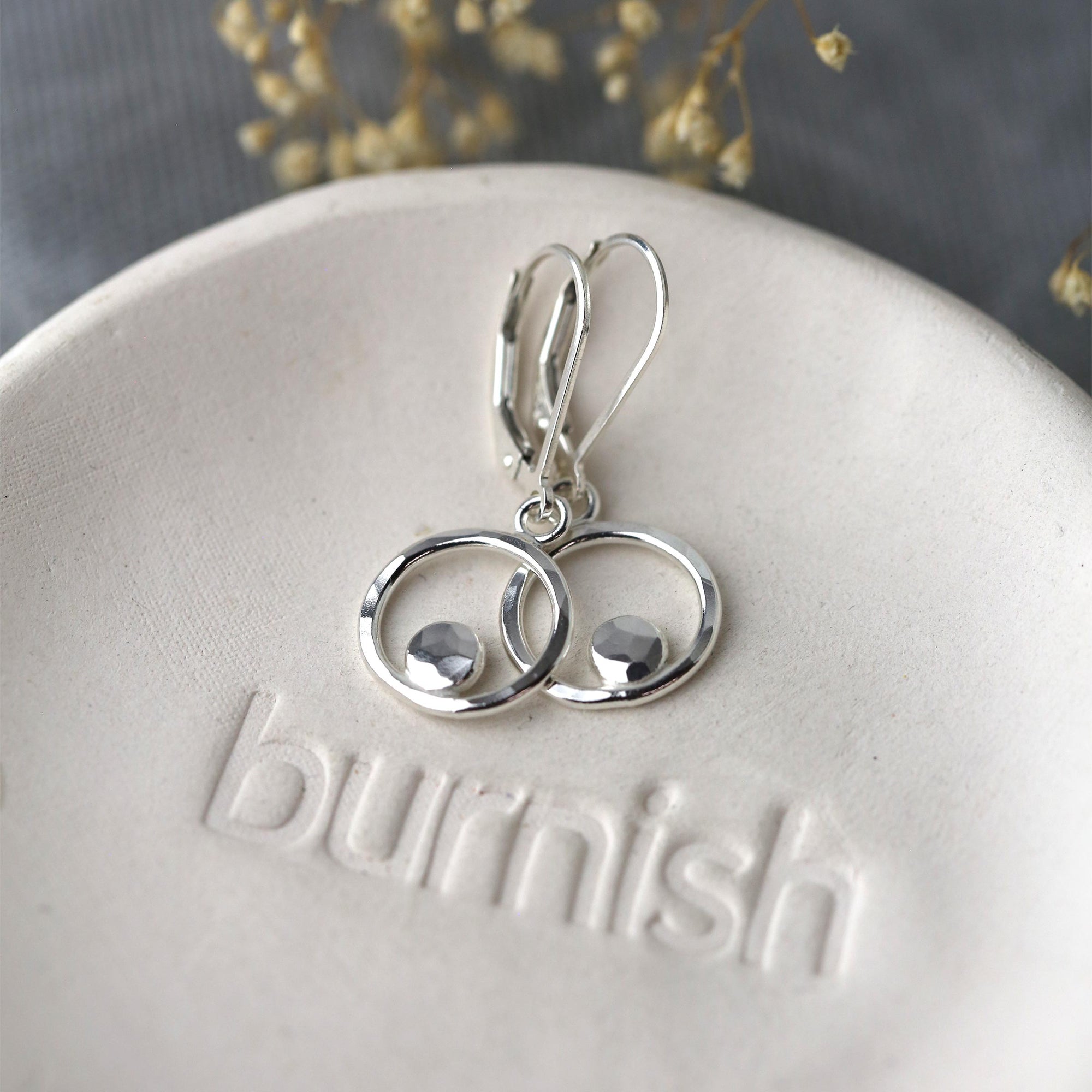 Silver earrings on a 'burnish' branded stone with a blurred natural background